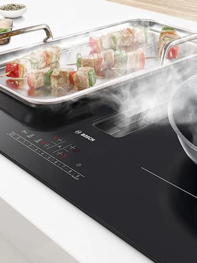 A modern kitchen featuring a black induction cooktop on a light wooden countertop.