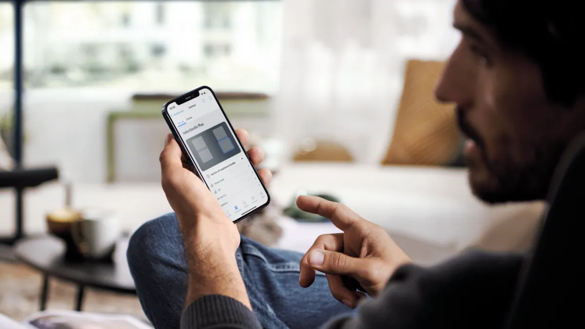 Man using smartphone in a cafe, close-up view of hands and mobile device.