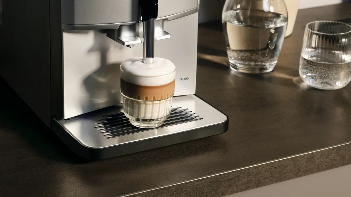 Outlet of the EQ300 fully automatic espresso machine, a cappuccino with milk foam is being prepared.