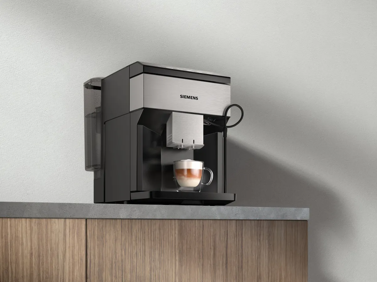 Coffee machine on wooden cabinet against gray wall.