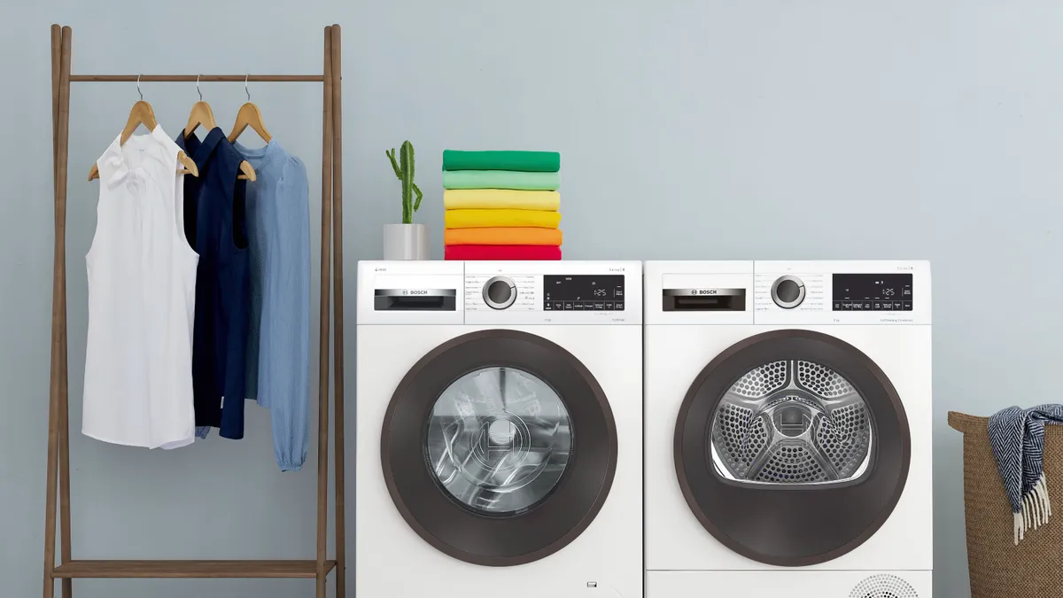 Laundry room with washing machine, dryer, clothes rack, and neatly folded towels.