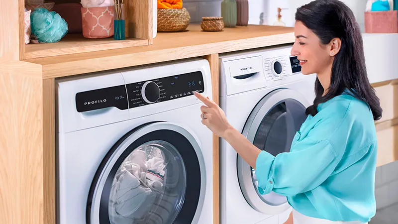 Kadın çamaşır makinesi çamaşır odasında raflarla çalışır.