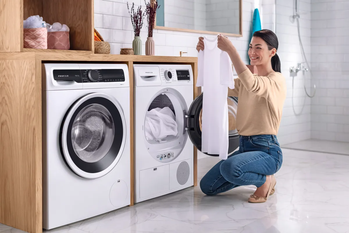 Kadın elbiseleri modern çamaşır odasında çamaşır makinesi ve kurutma makinesine yükler.