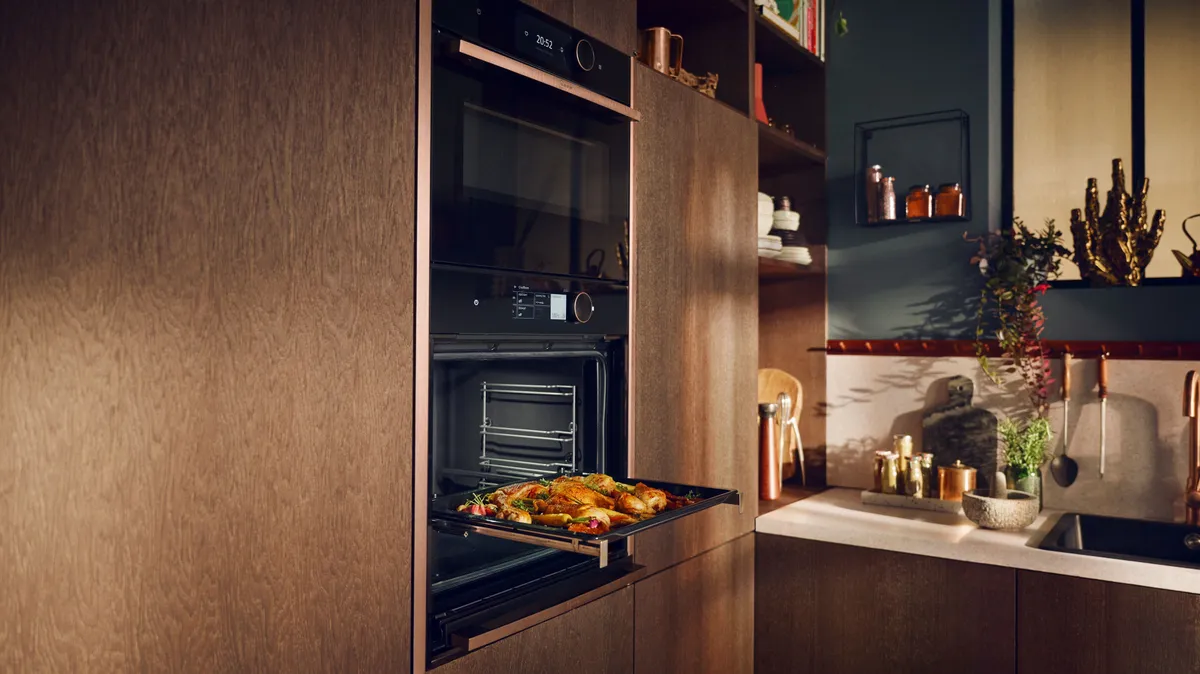 Moderne Küche mit offenem Ofen und gebratenem Essen, umgeben von stilvollen Schränken und dekorativen Küchenartikeln.