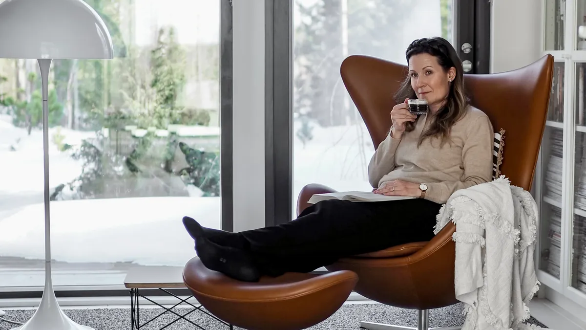 Kvinna dricker kaffe i en bekväm fåtölj