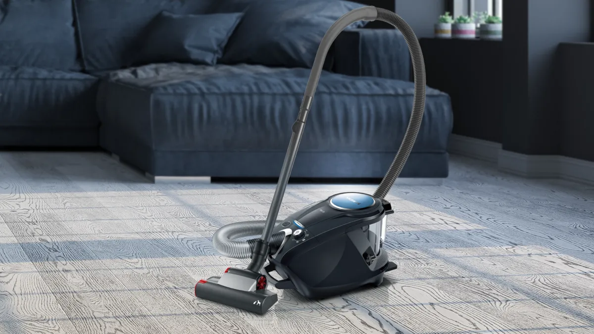 Oturma odasında karanlık kanepe ile sert ahşap zeminde elektrikli süpürge.