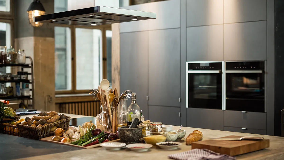 Island chimney hood in front of grey kitchen 