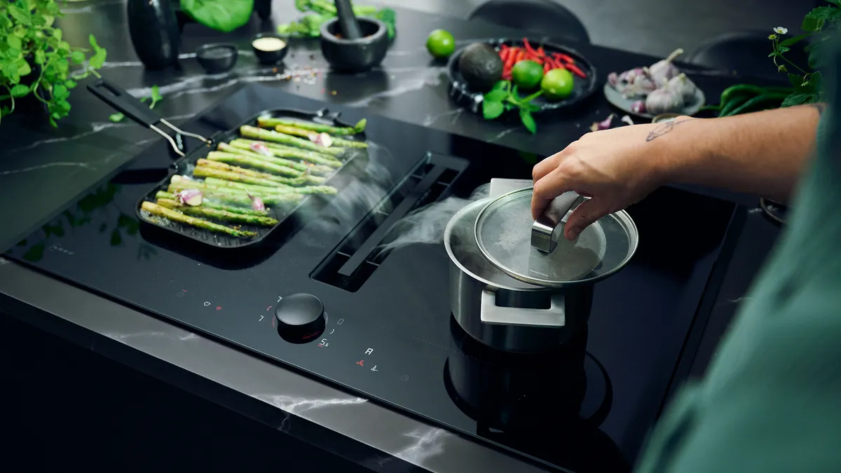 Cooking asparagus on a stovetop with various kitchen utensils and ingredients visible.