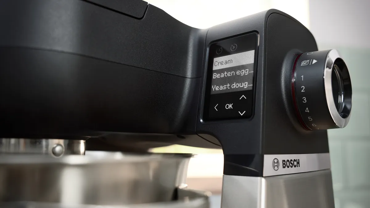 Close-up van een Bosch-keukenmixer, met een digitaal display waarop opties staan voor room, geklopte eieren en gistdeeg.