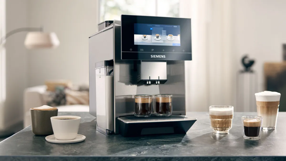 Dokunmatik ekranlı Siemens kahve makinesi, espresso bardak ve bir tezgahta diğer kahve aksesuarları.