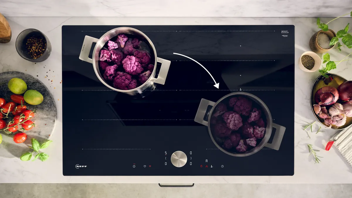 Ein modernes Kochfeld, auf dem zwei Töpfe mit lila Gemüse köcheln, umgeben von frischen Zutaten und Kochutensilien.