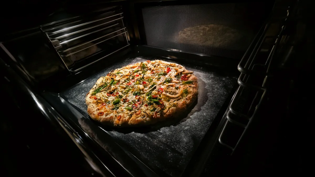Frisch gebackene Pizza mit Paprika, Gemüse und geschmolzenem Käse in einem dunklen Ofen.