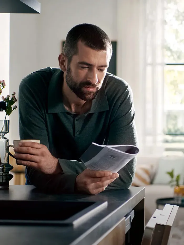 Un hombre joven consulta el manual de instrucciones de su electrodoméstico Siemens.