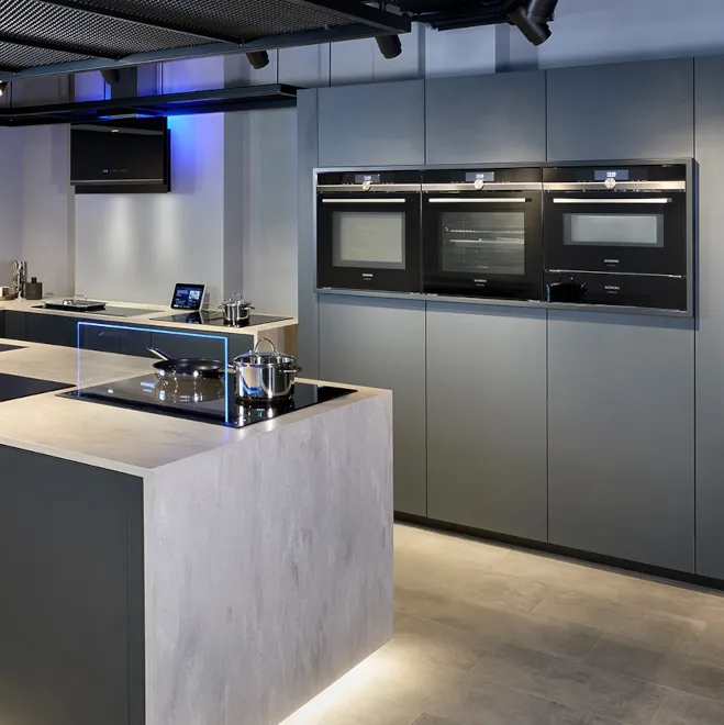 A sleek modern kitchen with two built in Siemens ovens stacked on top of each other.