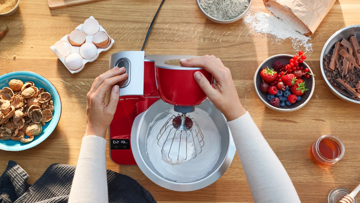 Malzemeler, mutfak aletleri ve bir ahşap masada kırmızı stand karıştırıcı kullanarak eller.