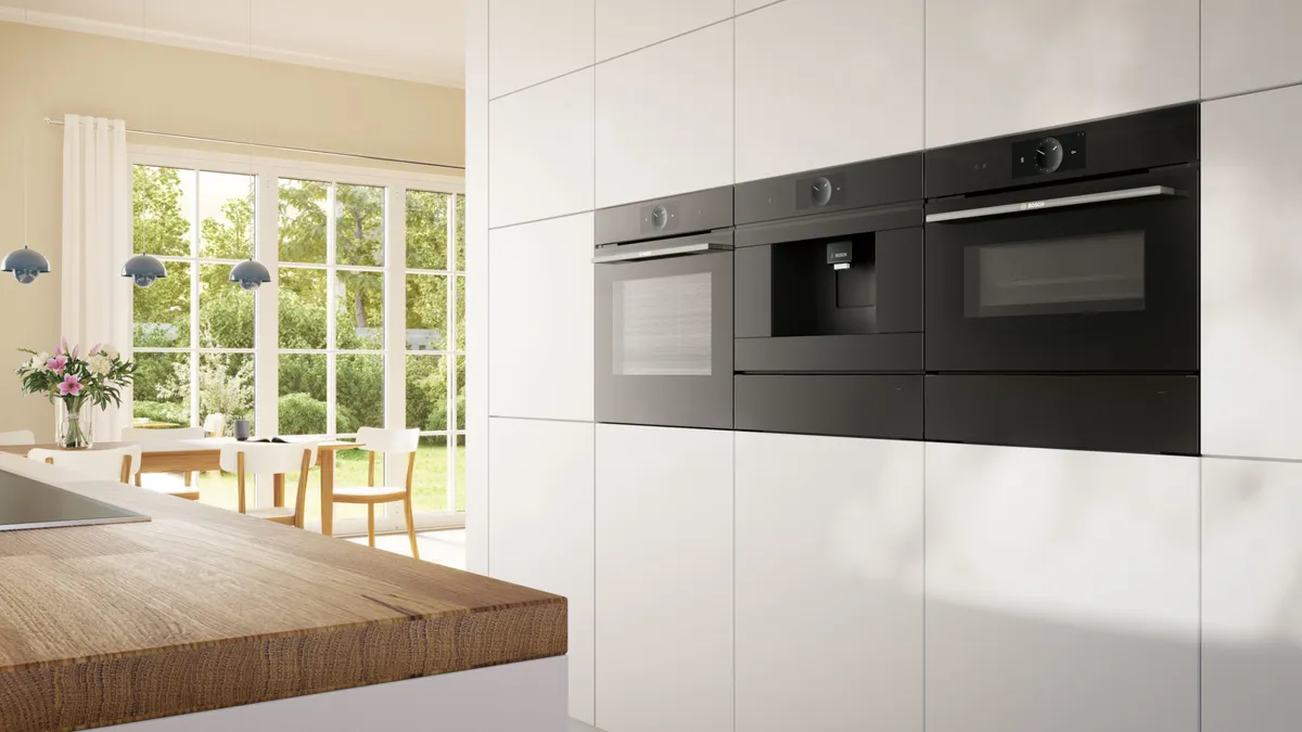 Büyük pencereler, ahşap masa ve ankastre aletlerle donatılmış modern mutfak.