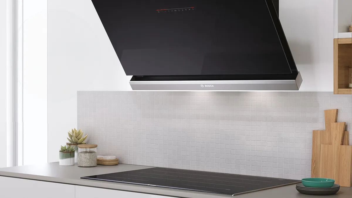 Siyah aralık hood ile modern mutfak, indüksiyon aşçıtop ve dekoratif bitkiler tezgahta.