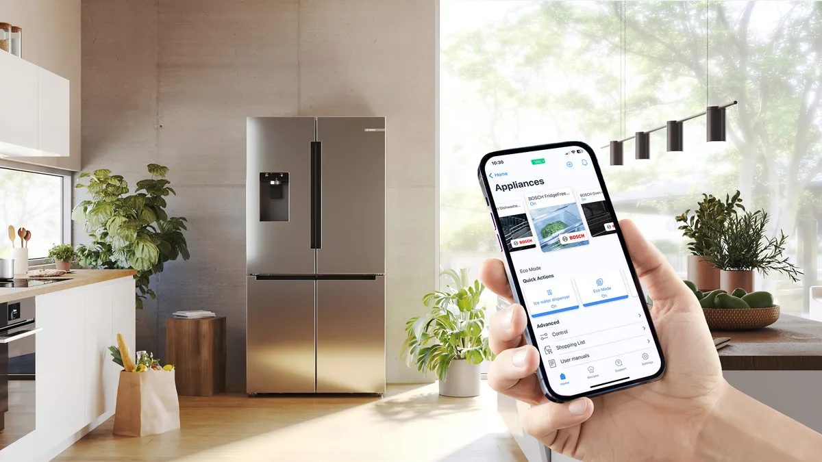 Widok z przodu chłodziarko-zamrażarki Multi Door z szybkim dystrybutorem lodu i wody w pomieszczeniu kuchennym, smartfon z ekranem Home Connect na pierwszym planie.