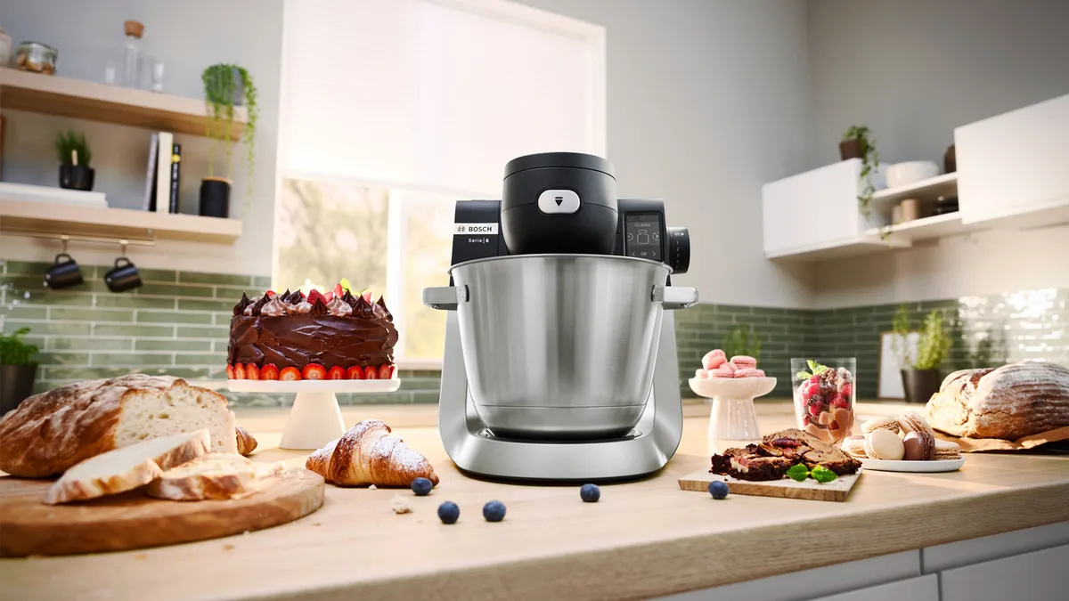 Kitchen counter with baked goods, mixer, and various food items.