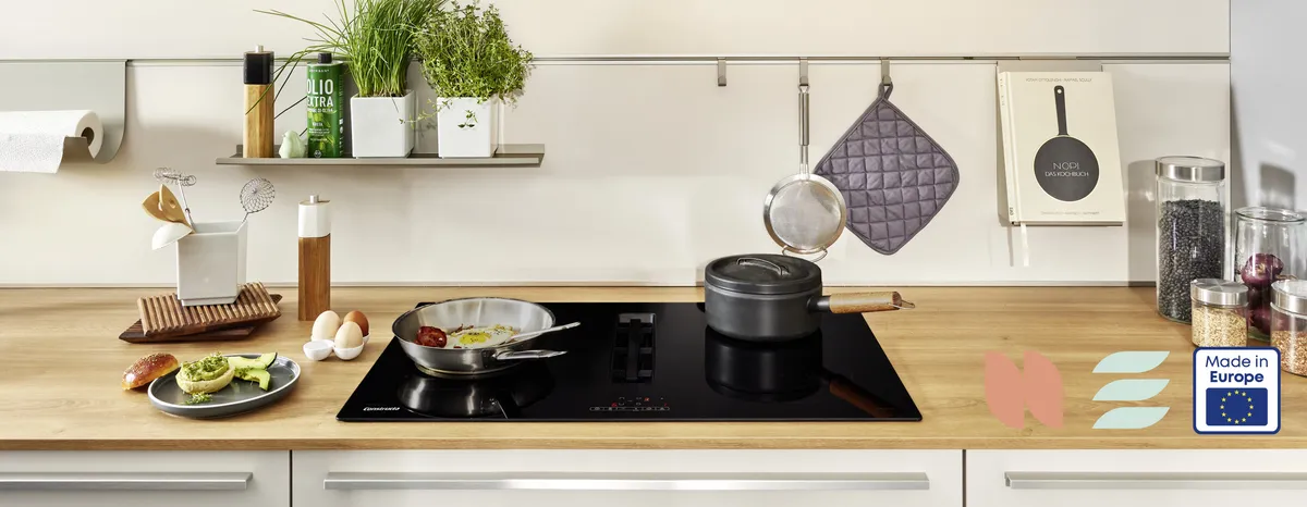 Küchentisch mit Kochutensilien, Topfpflanzen und Geräte auf einer Holzoberfläche.