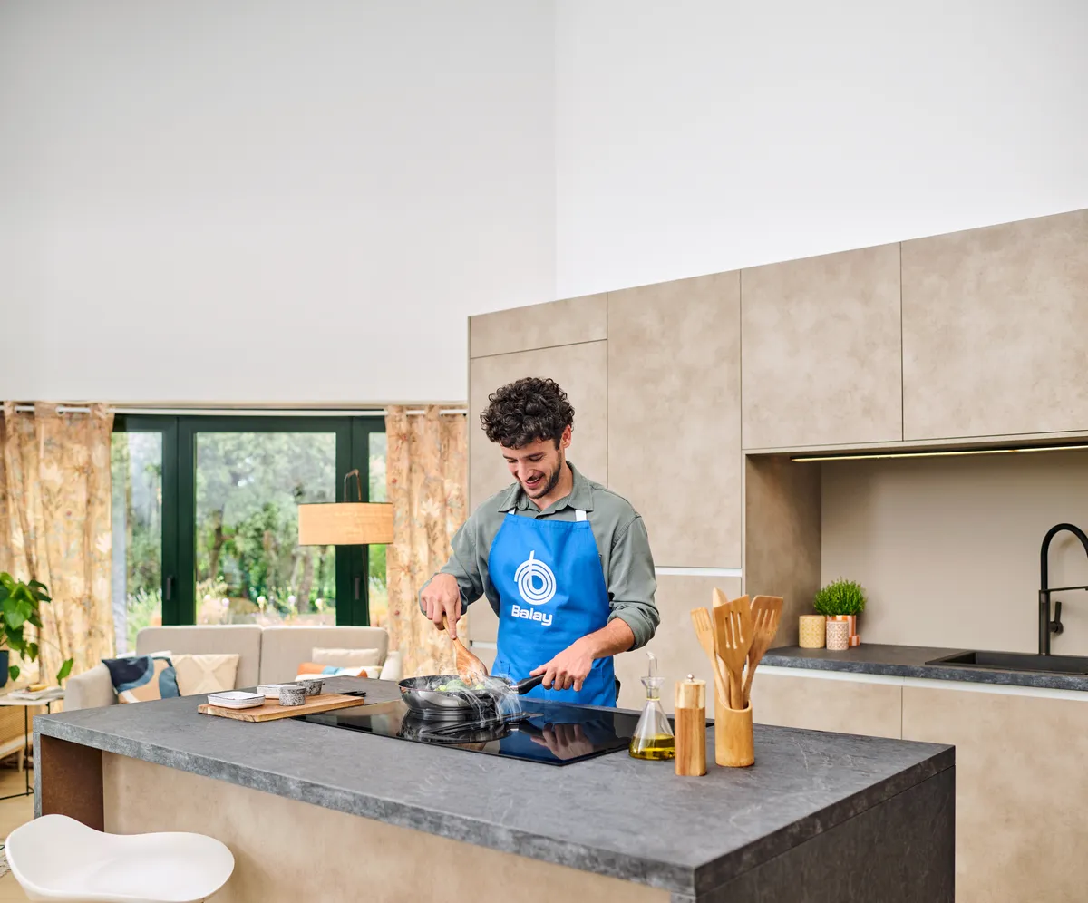 Plano hombre con delantal azul Balay utilizando una placa con extractor integrado