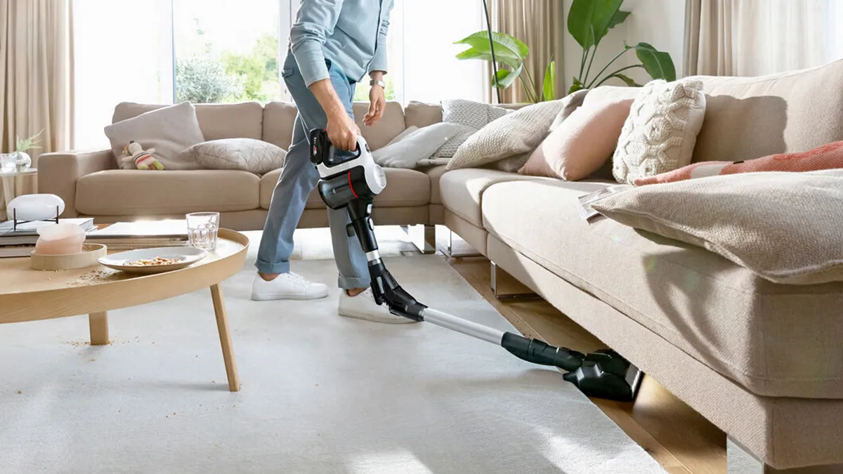 Person using Bosch vacuum flexible tube under sofa