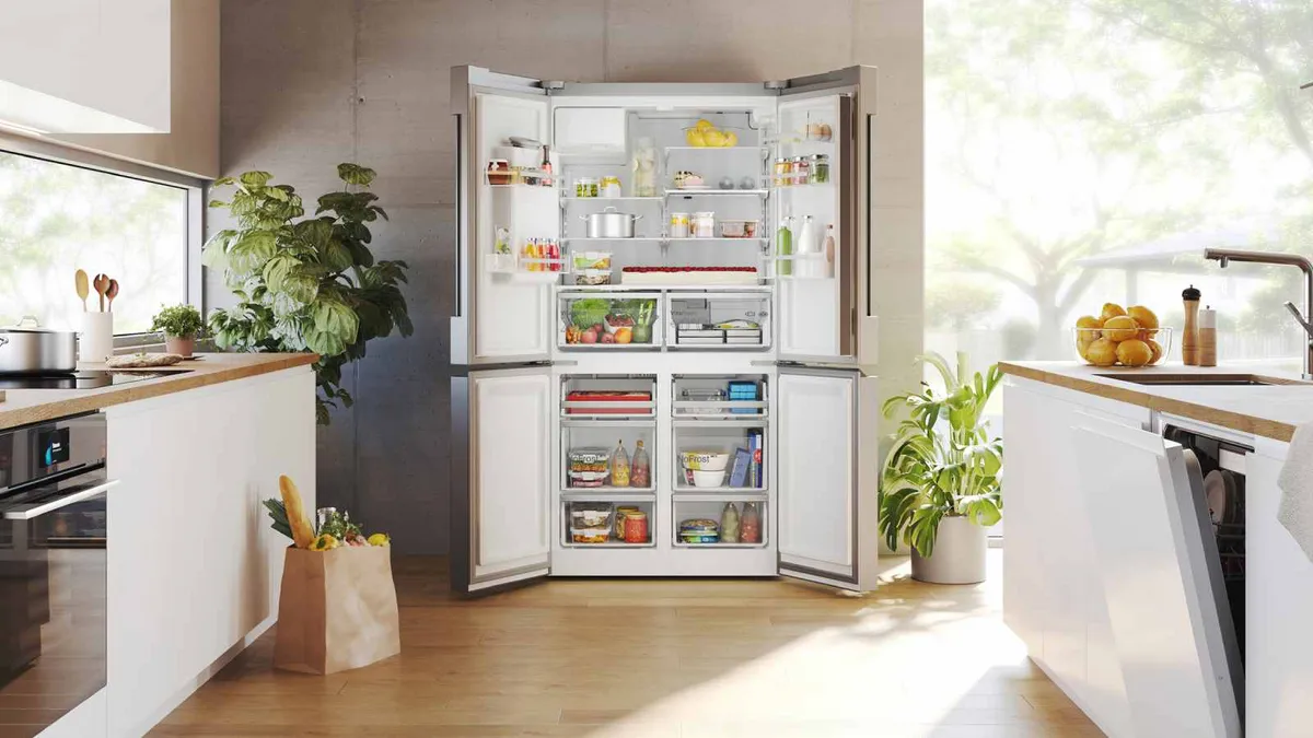 Ein geraumiger Kuhlschrank mit offenen Doppeltüren, gefullt mit verschiedenen Lebensmitteln, in einer hellen, modernen Kuche, umgeben von Pflanzen.