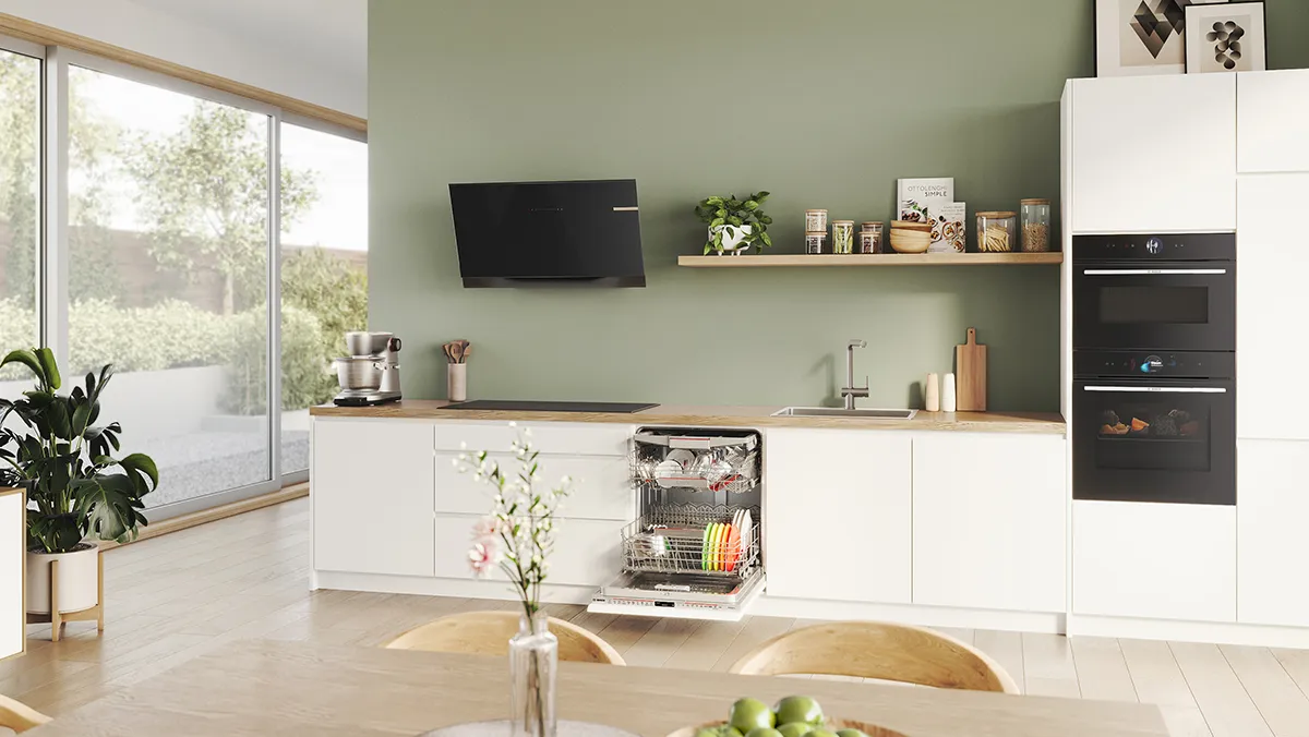 A view across a dining room table into a bright, modern kitchen full of Bosch appliances.