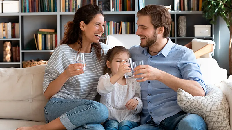 Oturma odasında kanepede birlikte üç zevk içecek ailesi.