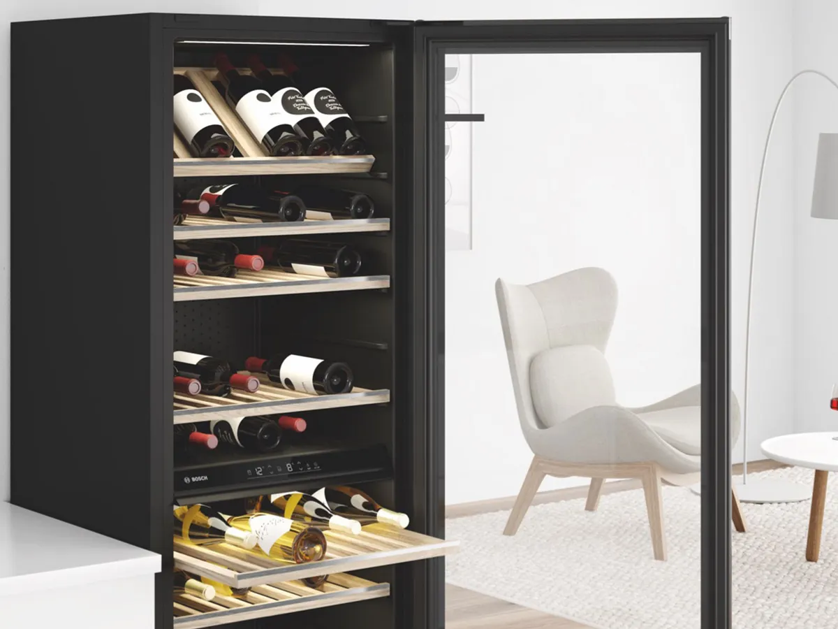Cave à vin Bosch noire ouverte avec clayettes en bois, bouteilles de vin et salon en arrière-plan.