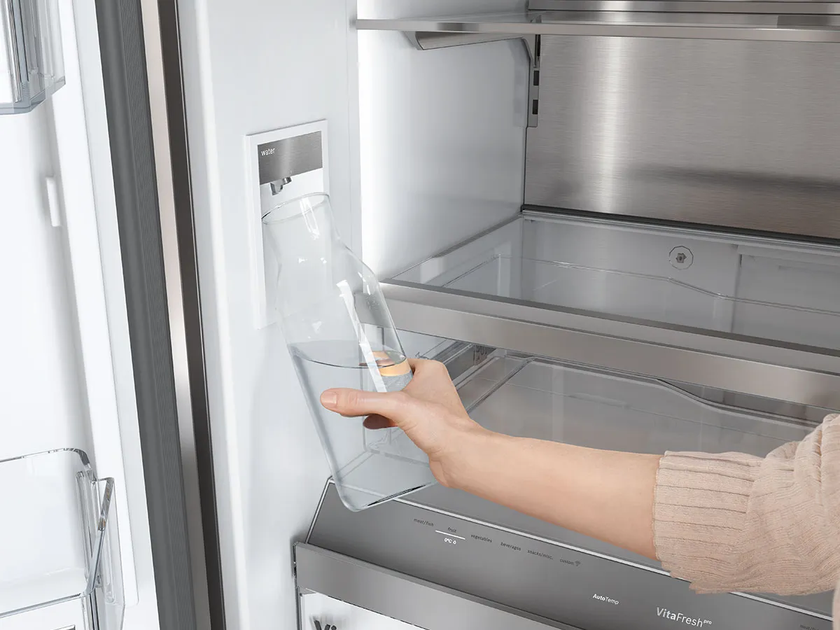 Remplissage d'une bouteille au distributeur d'eau intégré dans un réfrigérateur Bosch.