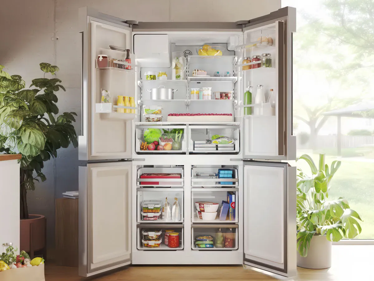 Réfrigérateur multi-portes Bosch ouvert, plein de produits frais, dans une cuisine ensoleillée.