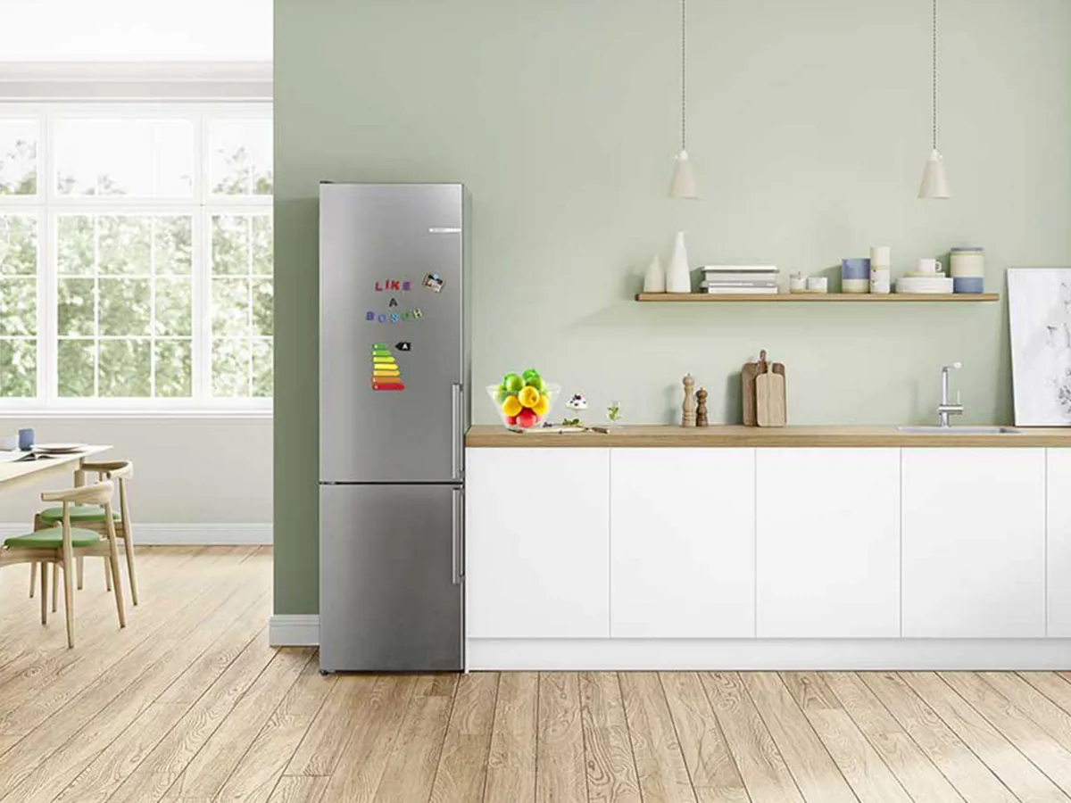 Réfrigérateur-congélateur Bosch en inox dans une cuisine moderne avec magnets colorés.