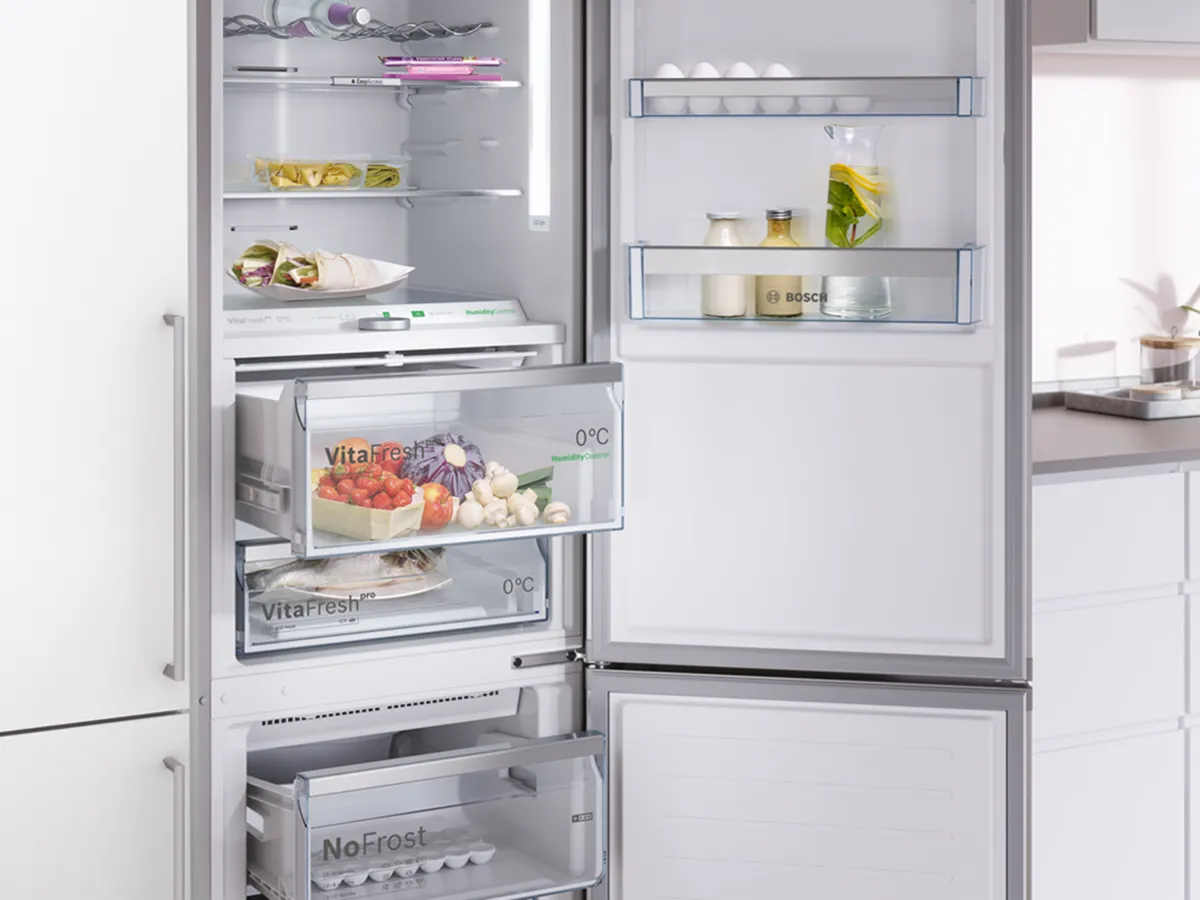Réfrigérateur-congélateur Bosch ouvert avec compartiments VitaFresh et NoFrost remplis d'aliments.