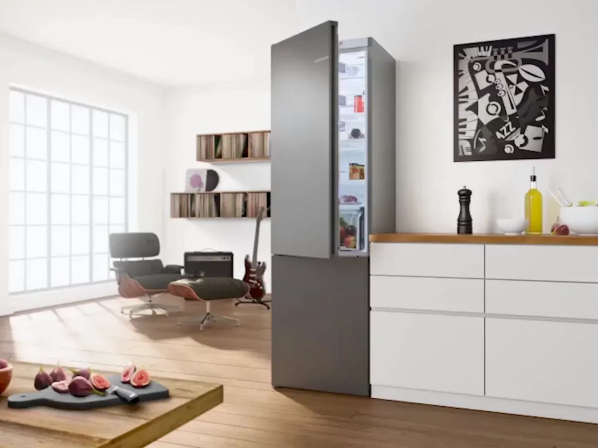Cuisine moderne avec un réfrigérateur Bosch gris ouvert, révélant des aliments frais à l’intérieur.
