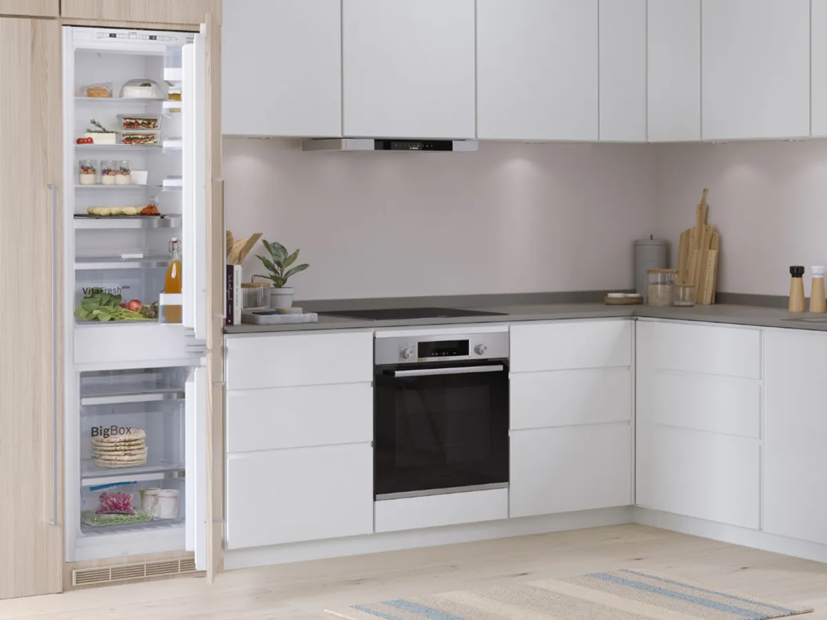 Cuisine avec réfrigérateur encastrable ouvert montrant un rangement organisé des aliments.