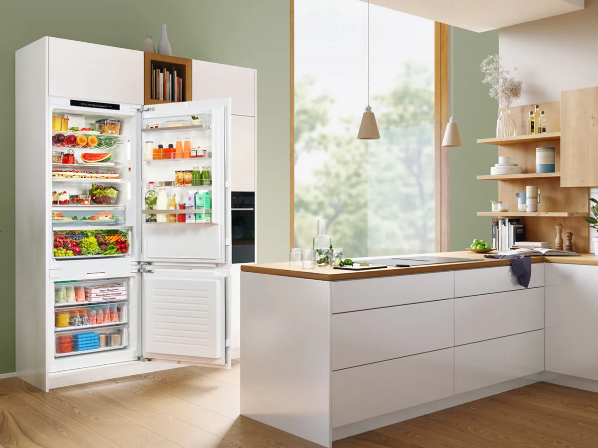 Cuisine moderne avec un grand réfrigérateur-congélateur encastré, porte ouverte et bien rempli.
