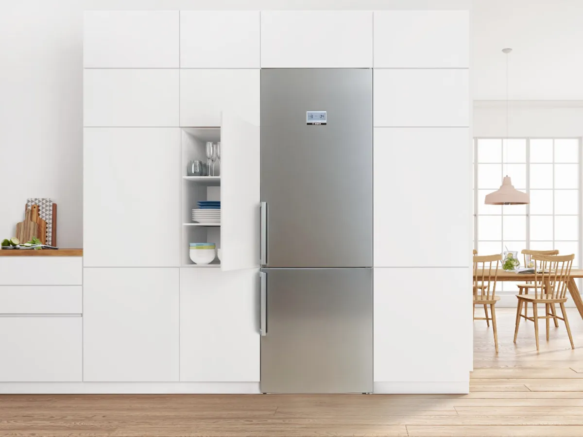 Cuisine moderne dotée d'un élégant réfrigérateur en acier inoxydable avec porte ouverte, entouré d'armoires blanches minimalistes et d'un coin repas.