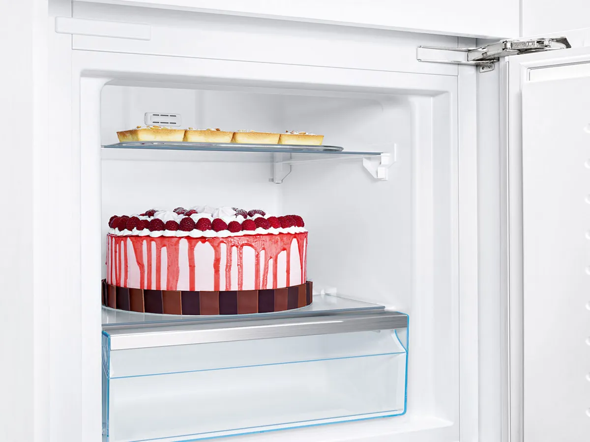 Gâteau et tartes sur une étagère dans un congélateur Bosch blanc avec tiroir transparent.