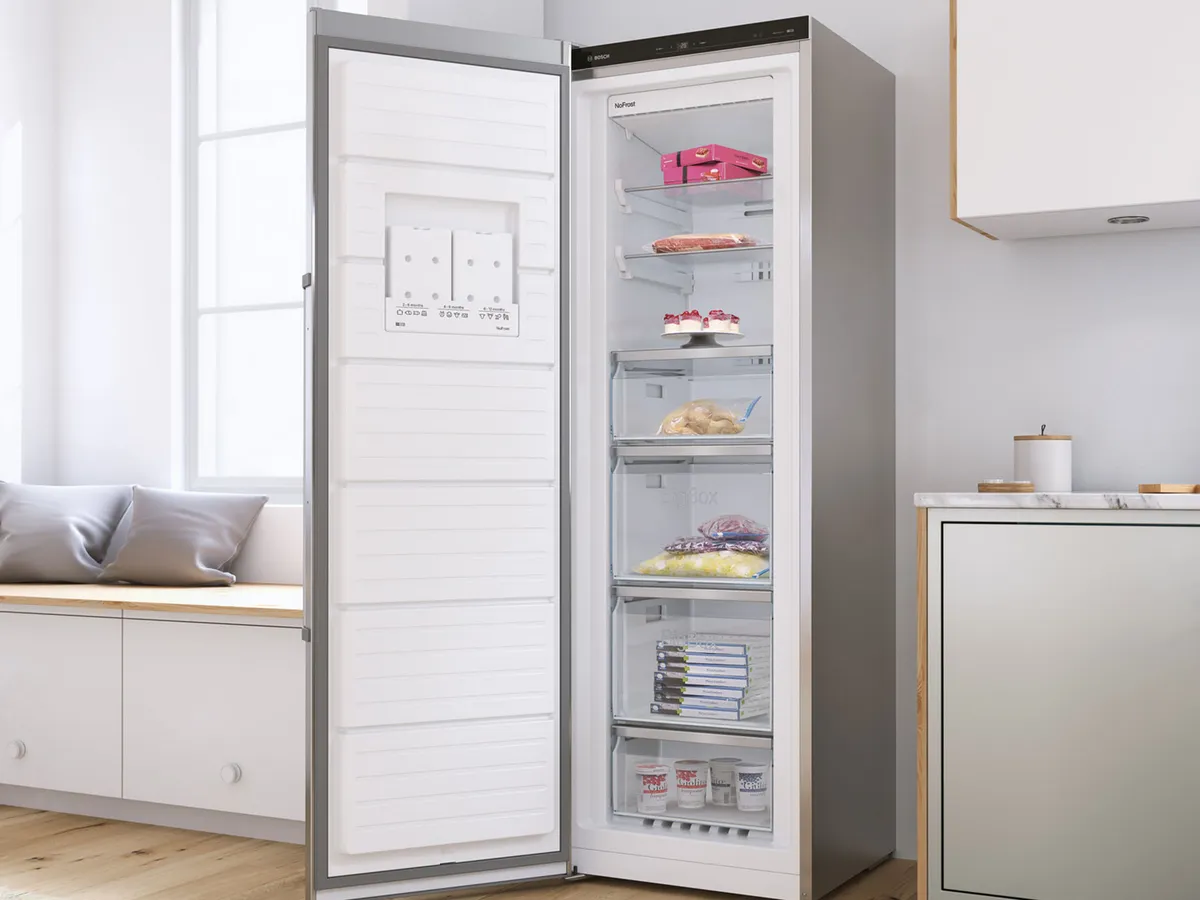 Réfrigérateur moderne avec une porte ouverte affichant des étagères organisées d'aliments, situé dans une cuisine lumineuse et élégante.