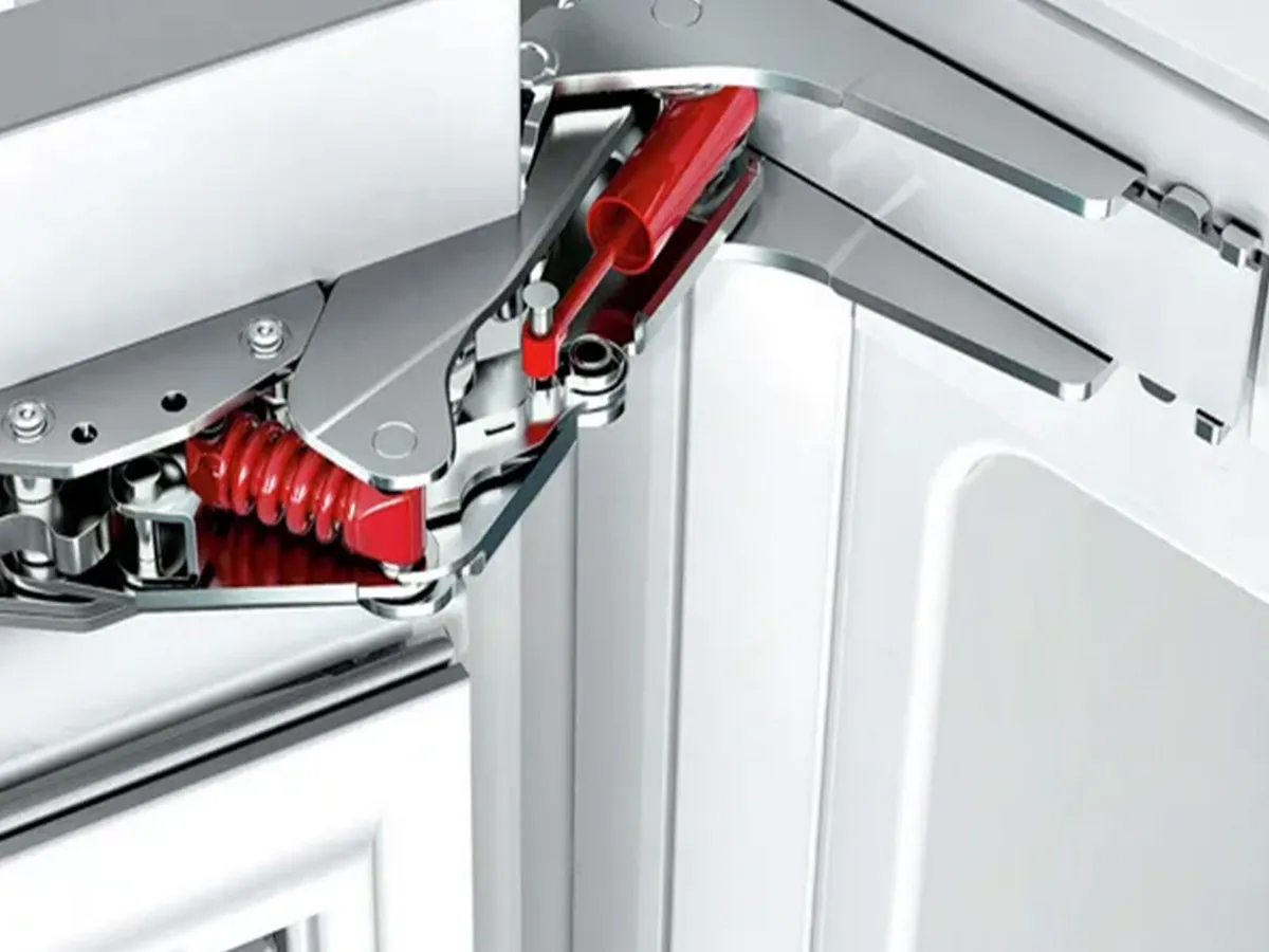 Gros plan sur le mécanisme de charnière d’une porte de réfrigérateur Bosch avec ressort rouge.