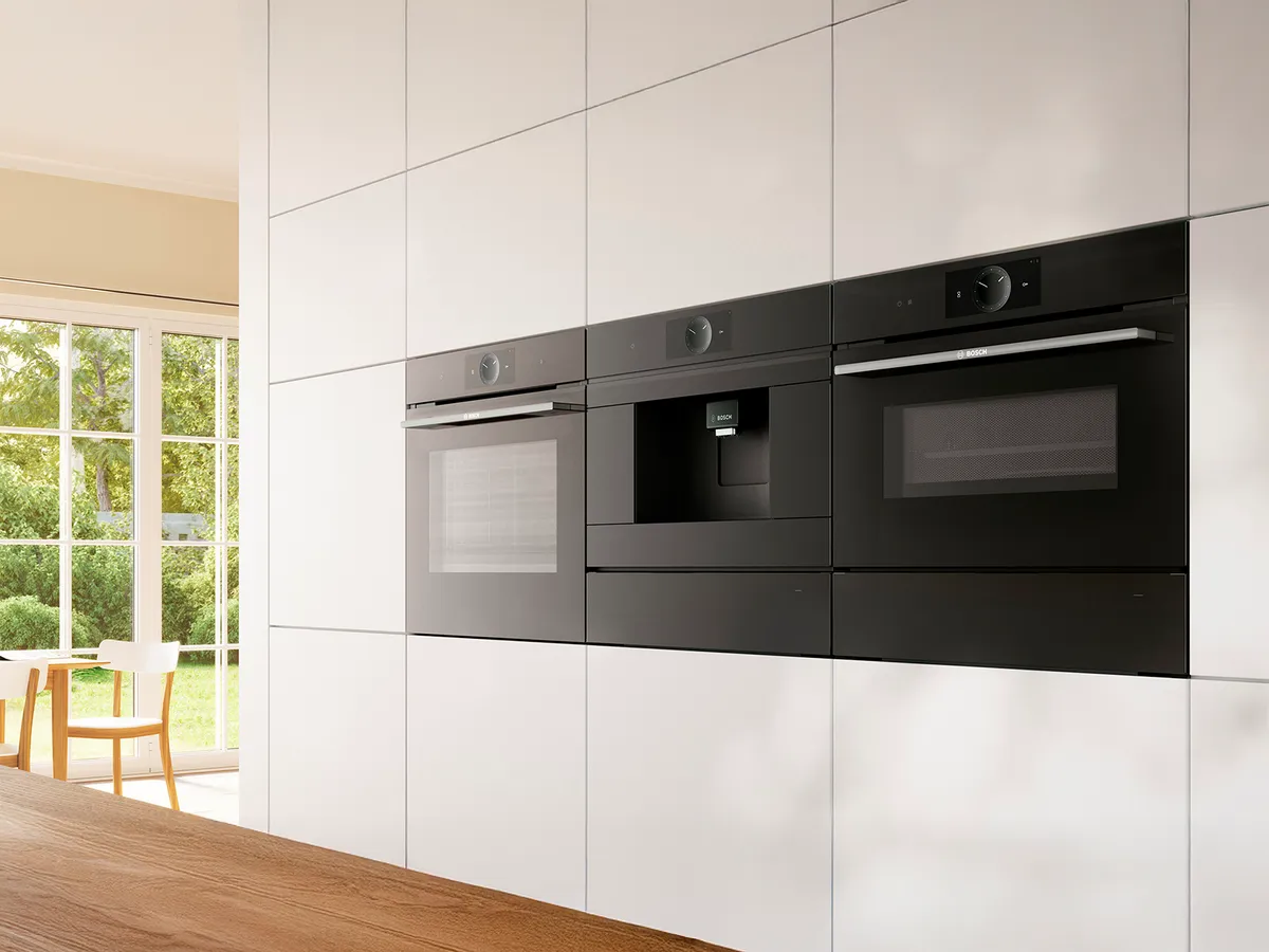 Atraente forno Bosch, máquina de café expresso e microondas integrados numa parede.