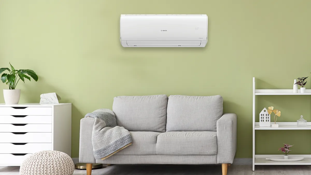 Gri kanepeli oturma odası, hava durumu ve yeşil duvara karşı helving ünitesi.