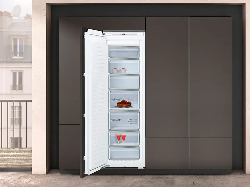 NEFF fryser med åpen dør, innebygd i en mørk skapvegg.