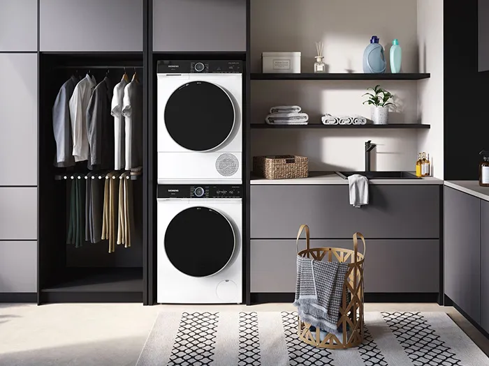 Minimalistische Waschküche mit schwarzen und weißen Schränken, Regalen und gestapelten Waschmaschinen.