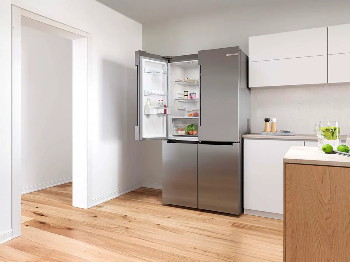 Frigorífico de portas francesas numa cozinha com a porta esquerda aberta.