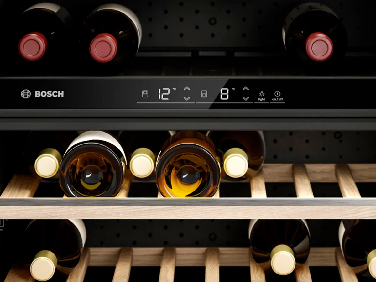 Digital kontrollpanel i en vinkyl med två temperaturzoner: rött vin högst upp, vitt vin på de lägre hyllorna.