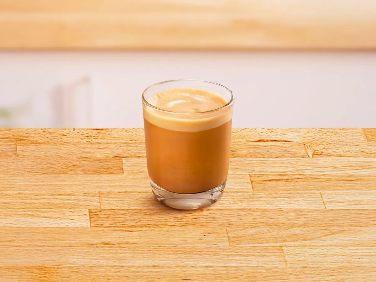 Glass cup filled with cortado coffee.