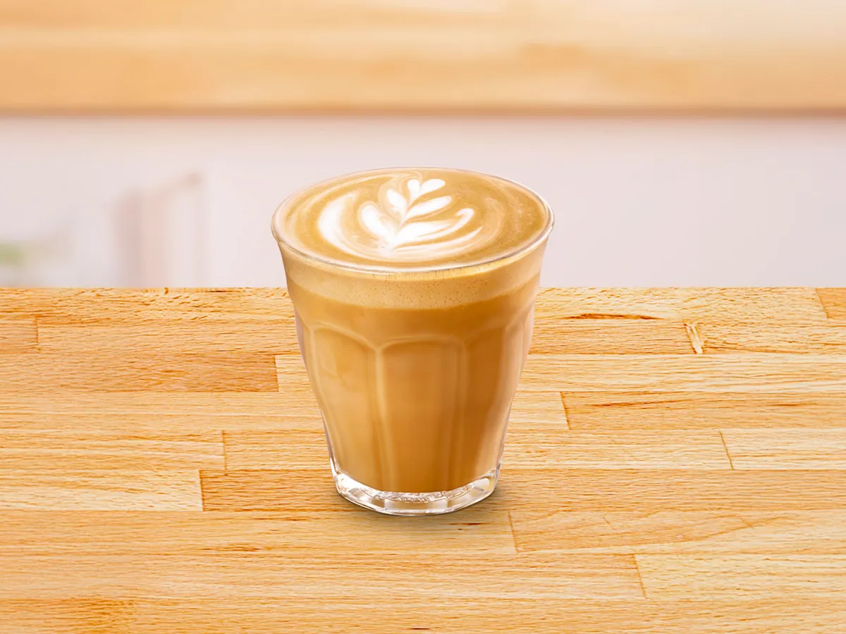 Glass cup filled with flat white coffee.