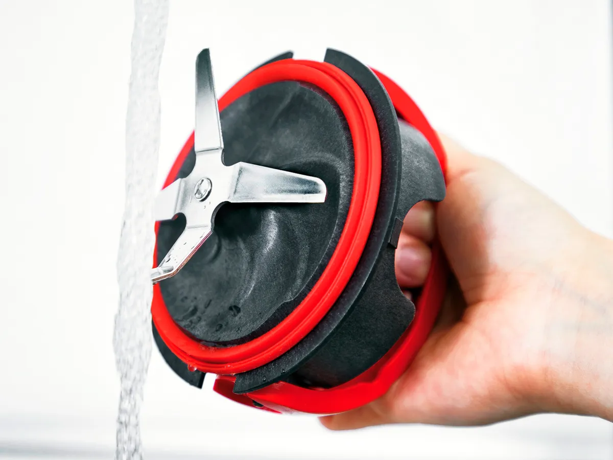 Unidade de lâmina do liquidificador Bosch sendo enxaguada sob água corrente, destacando seu design fácil de limpar para manutenção sem complicações.